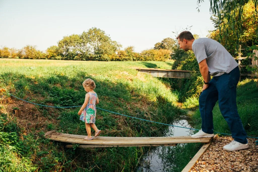 Dad helping his daughter across a stream