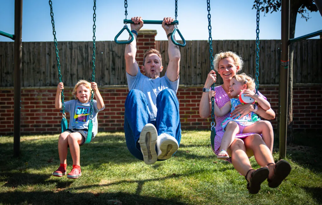 Family playing together on the garden swings