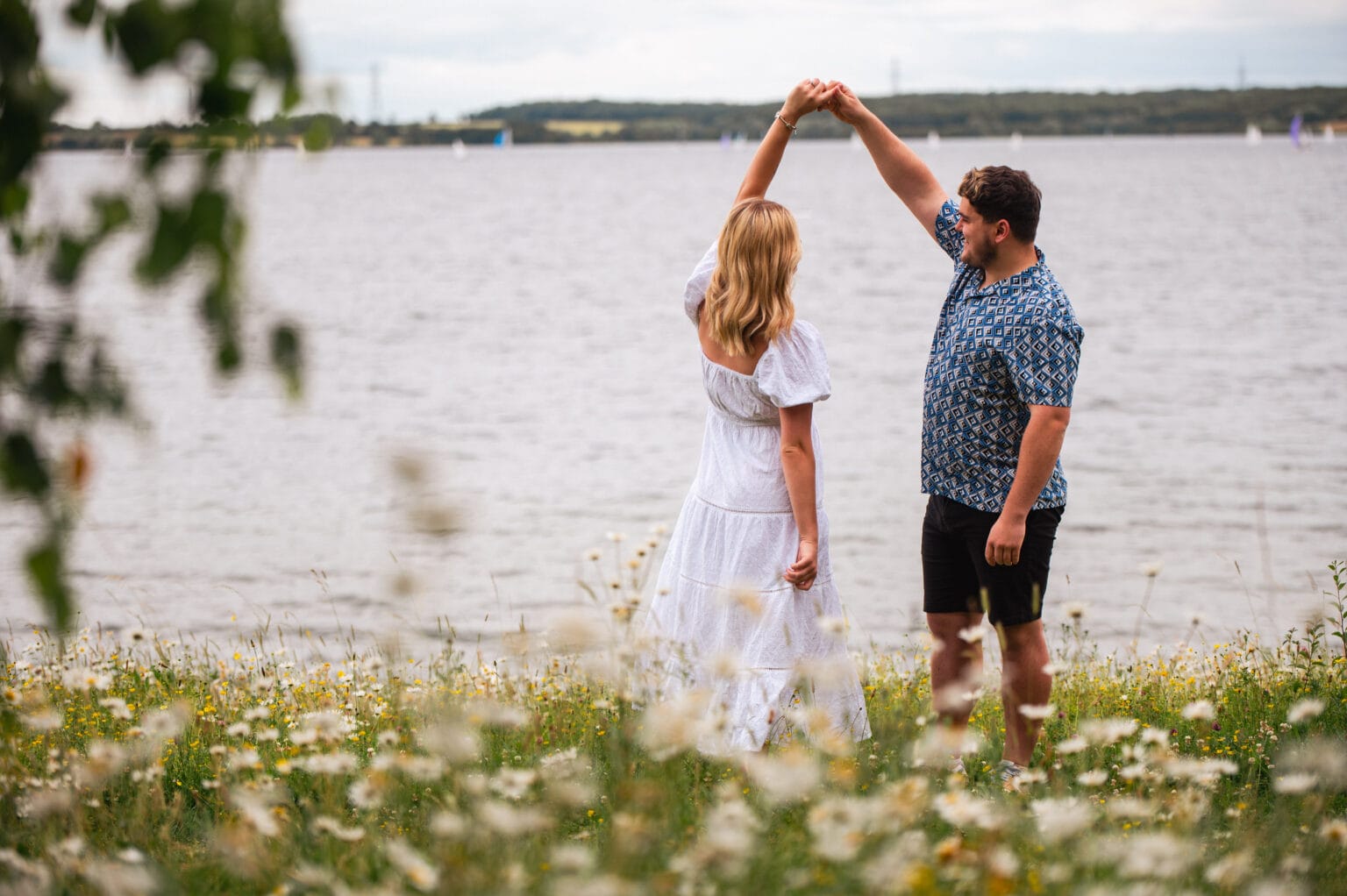 Couple dancing by the water among wild daisies