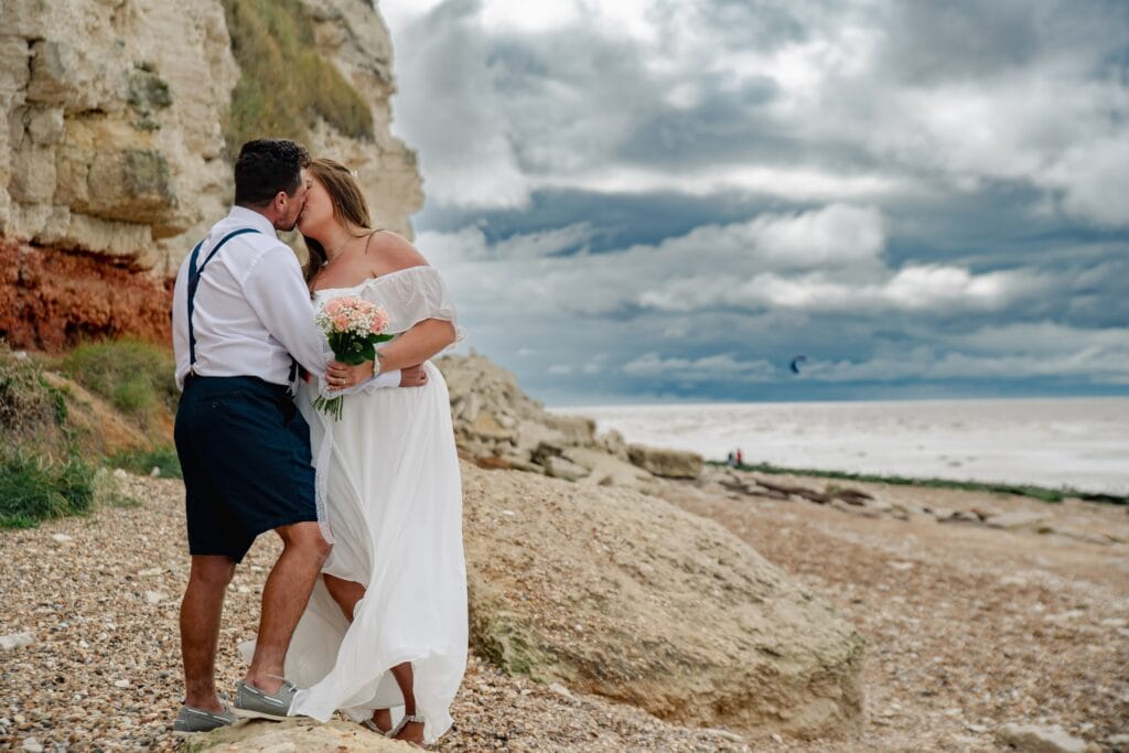 Couple standing on a pebble beach under a big sky
