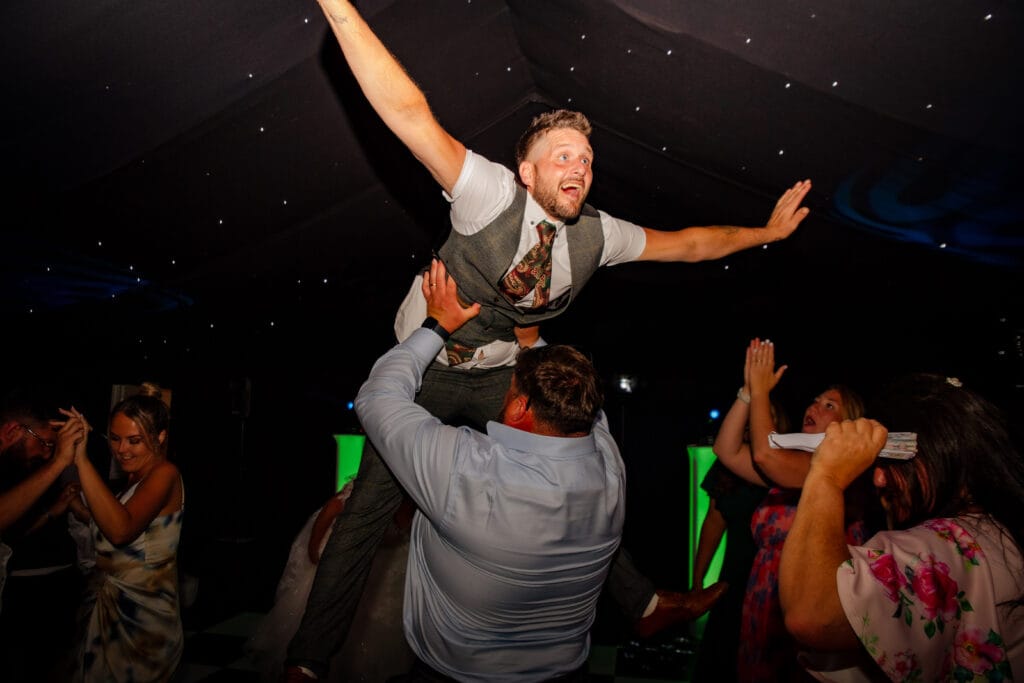 Groom crowd-surfing on the dance floor