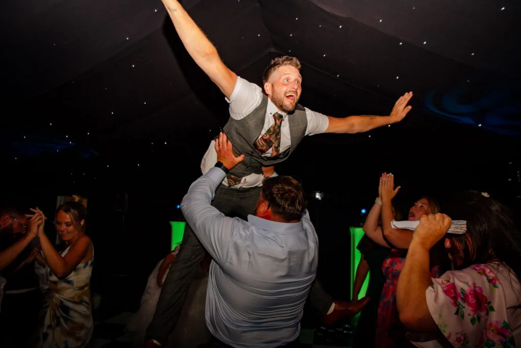 Groom crowd-surfing on the dance floor