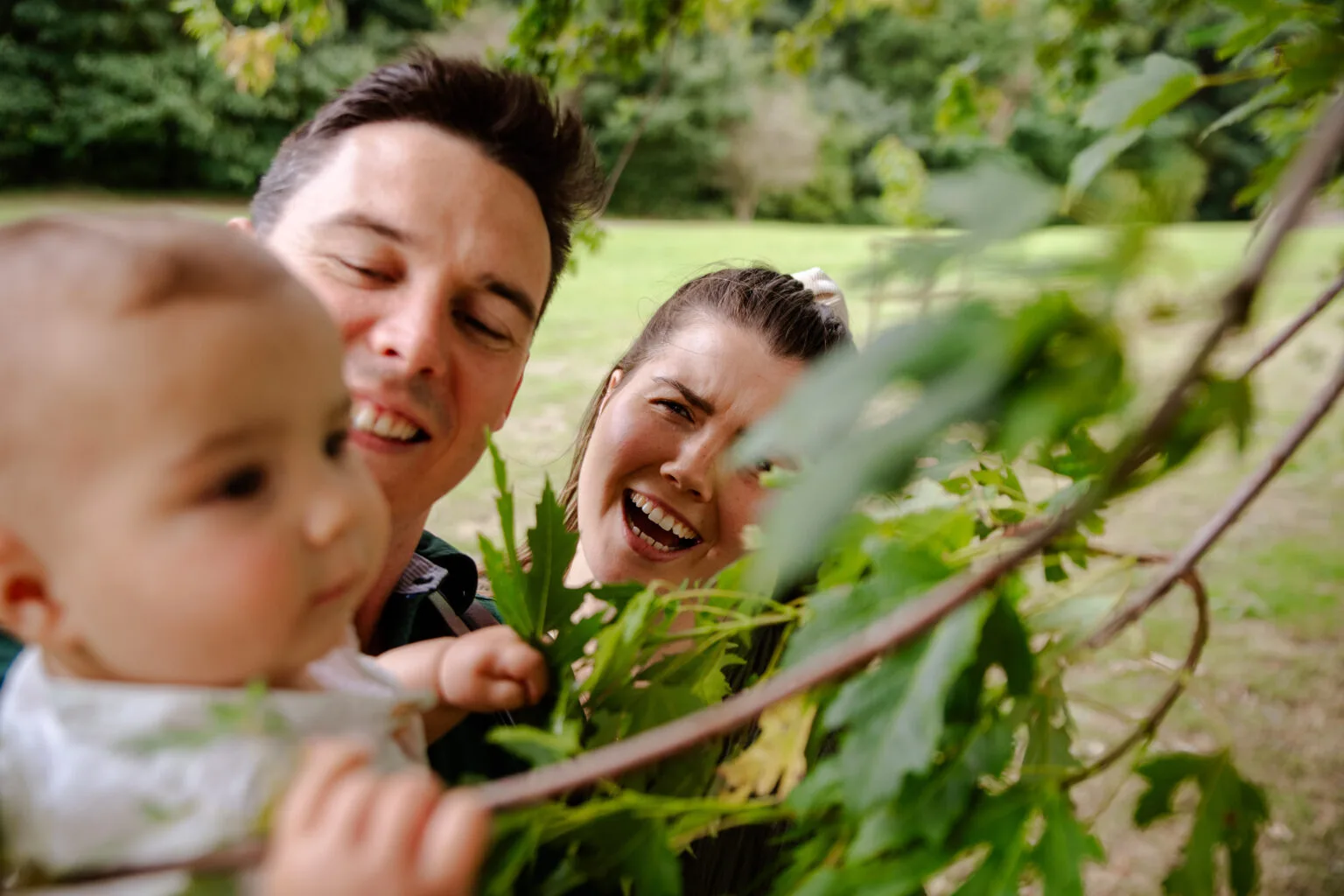 Baby reaching for leaves with mum and dad