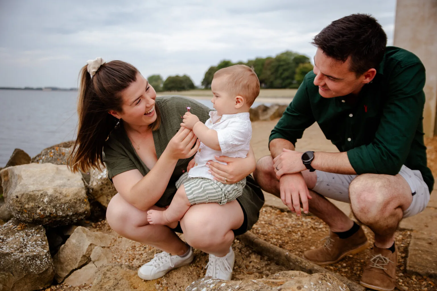 Parents playing with their baby on the rocks by the water