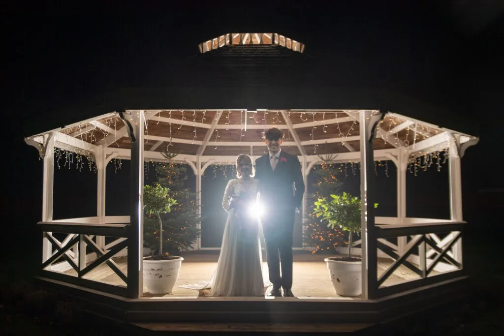 Couple framed by a lit gazebo at night