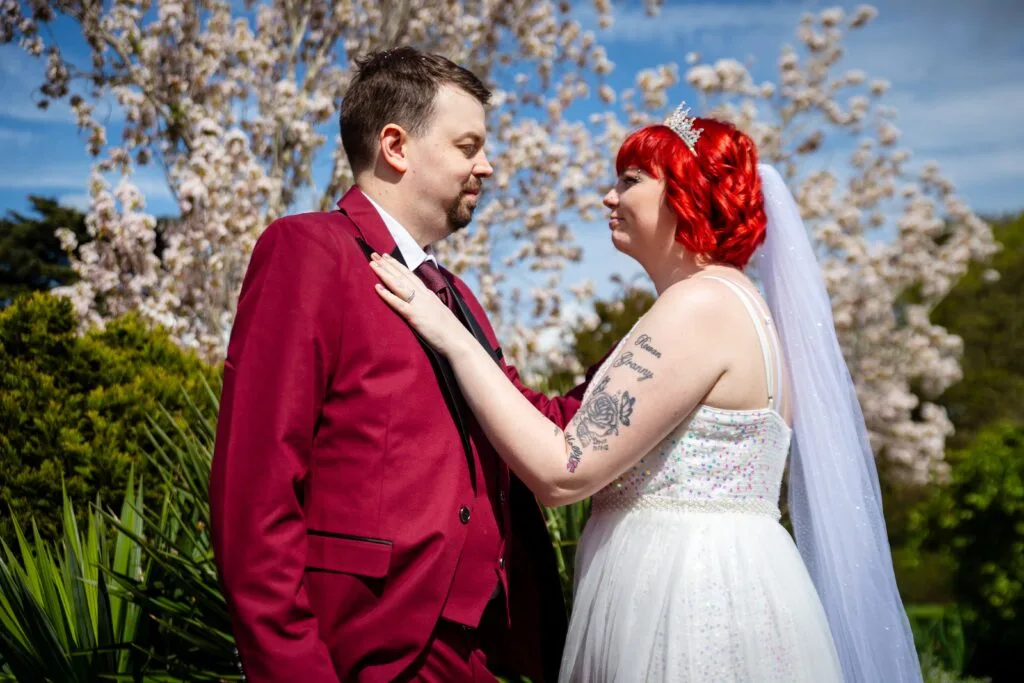 Groom in a red jacket with his bride among blossom