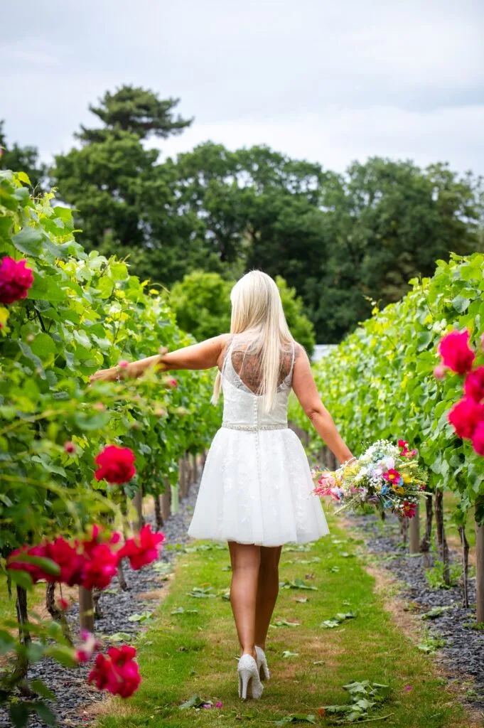 Bride walking between rows of vines
