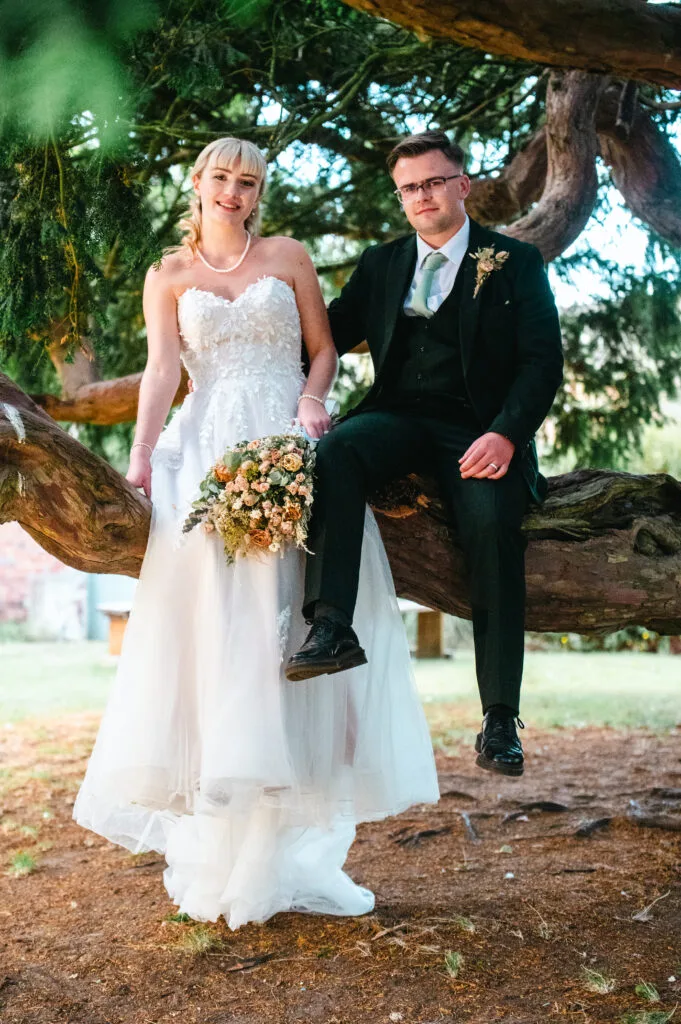 Bride and groom standing close under a tree