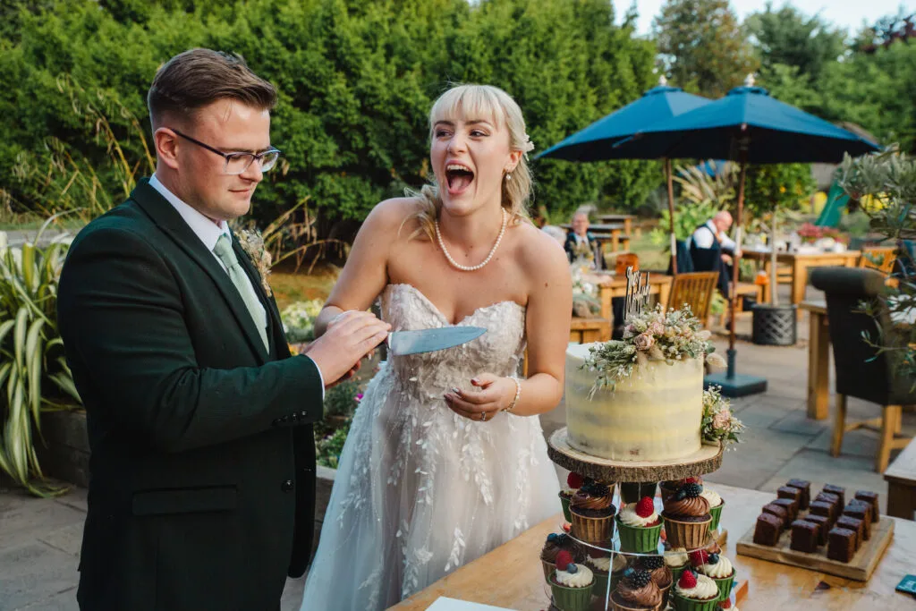 Couple laughing as they cut the cake outside