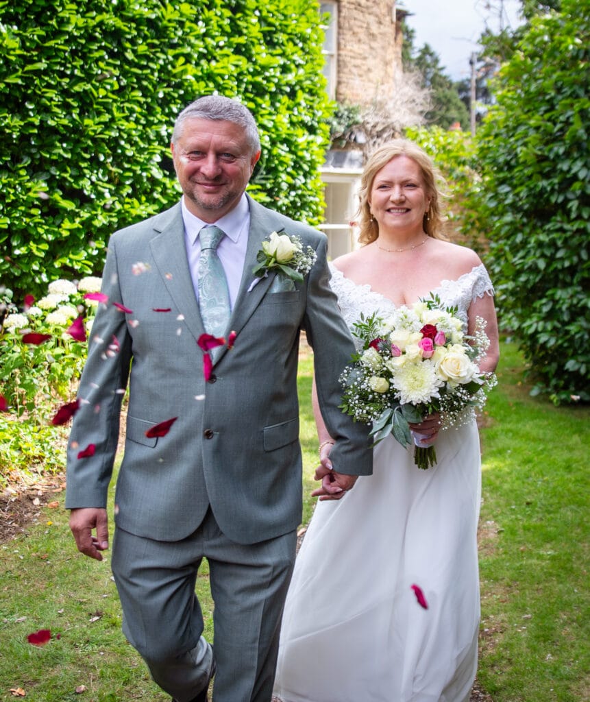 Bride and groom walking along a leafy path