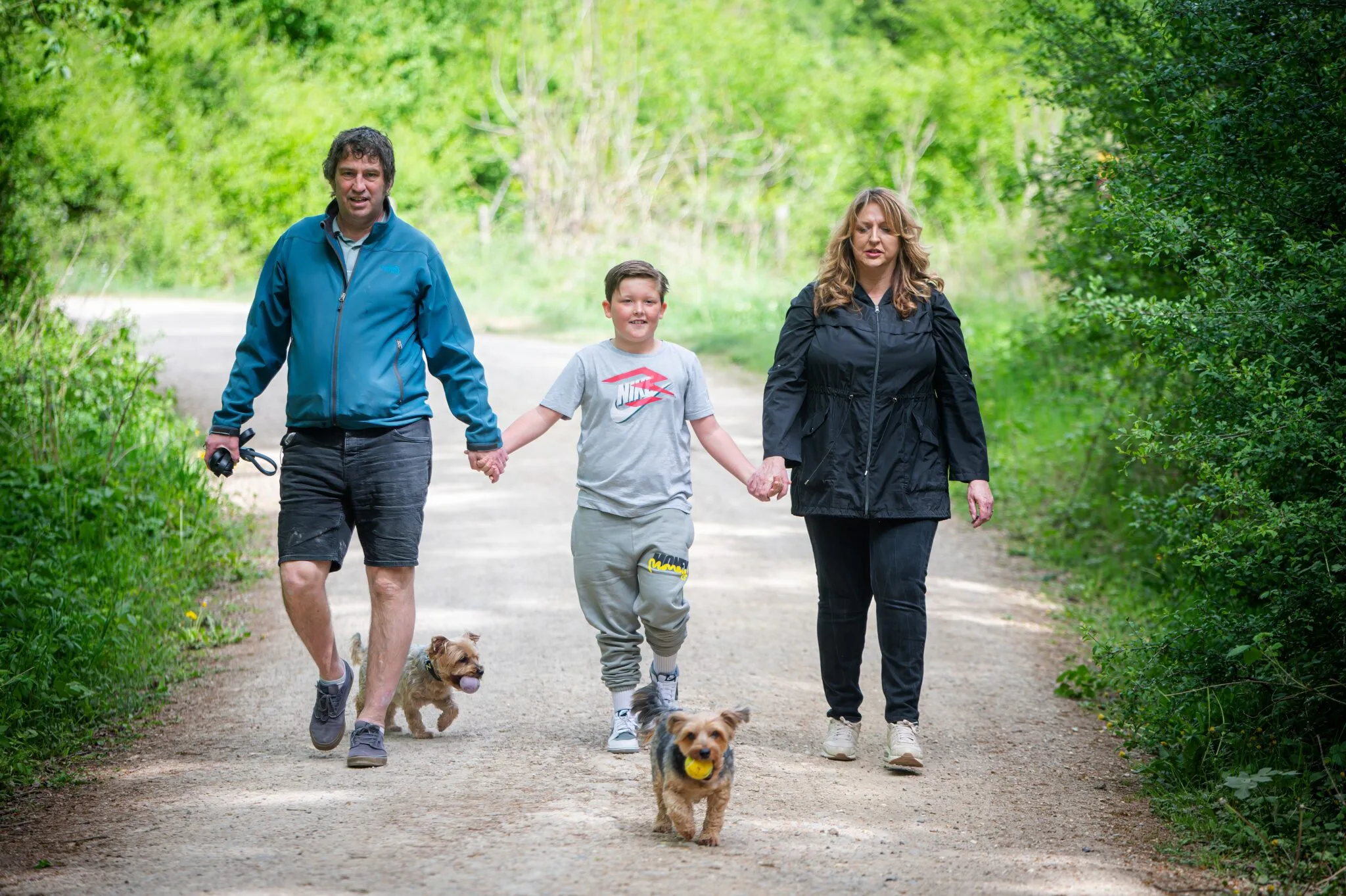 Family walking their dogs down a leafy lane
