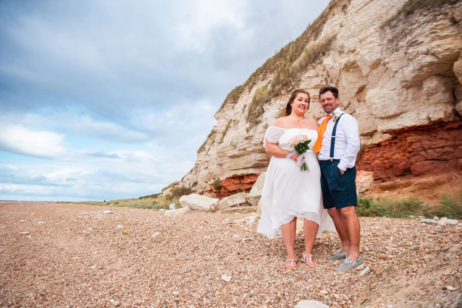 Couple on a beach beneath red cliffs