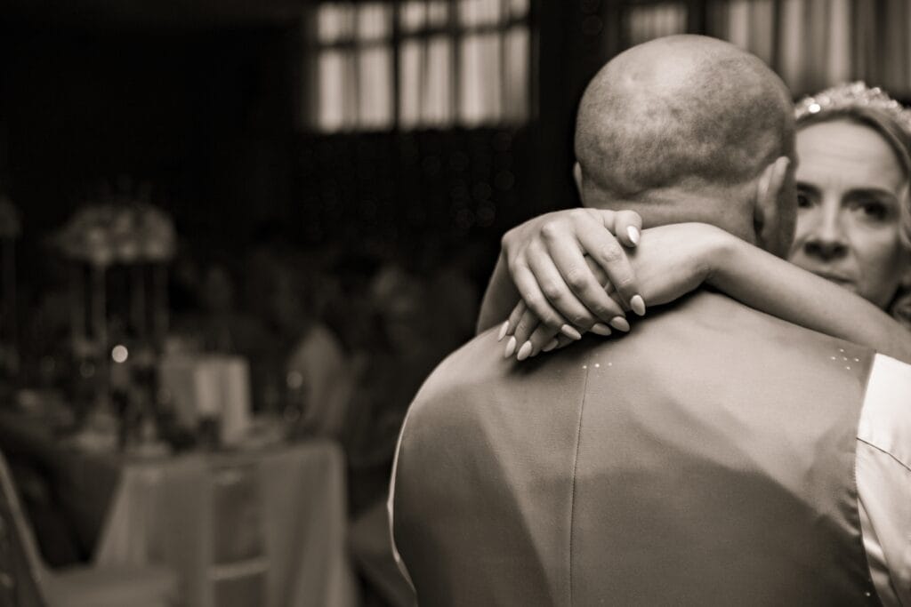 Black and white photo of a guest hugging the groom