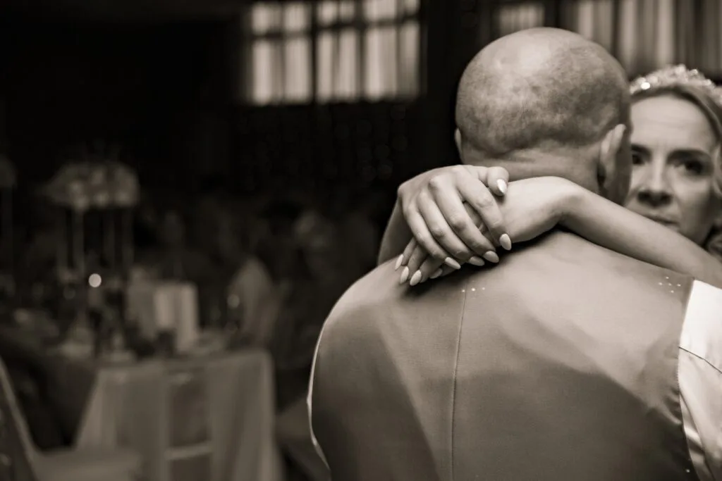Black and white photo of a guest hugging the groom