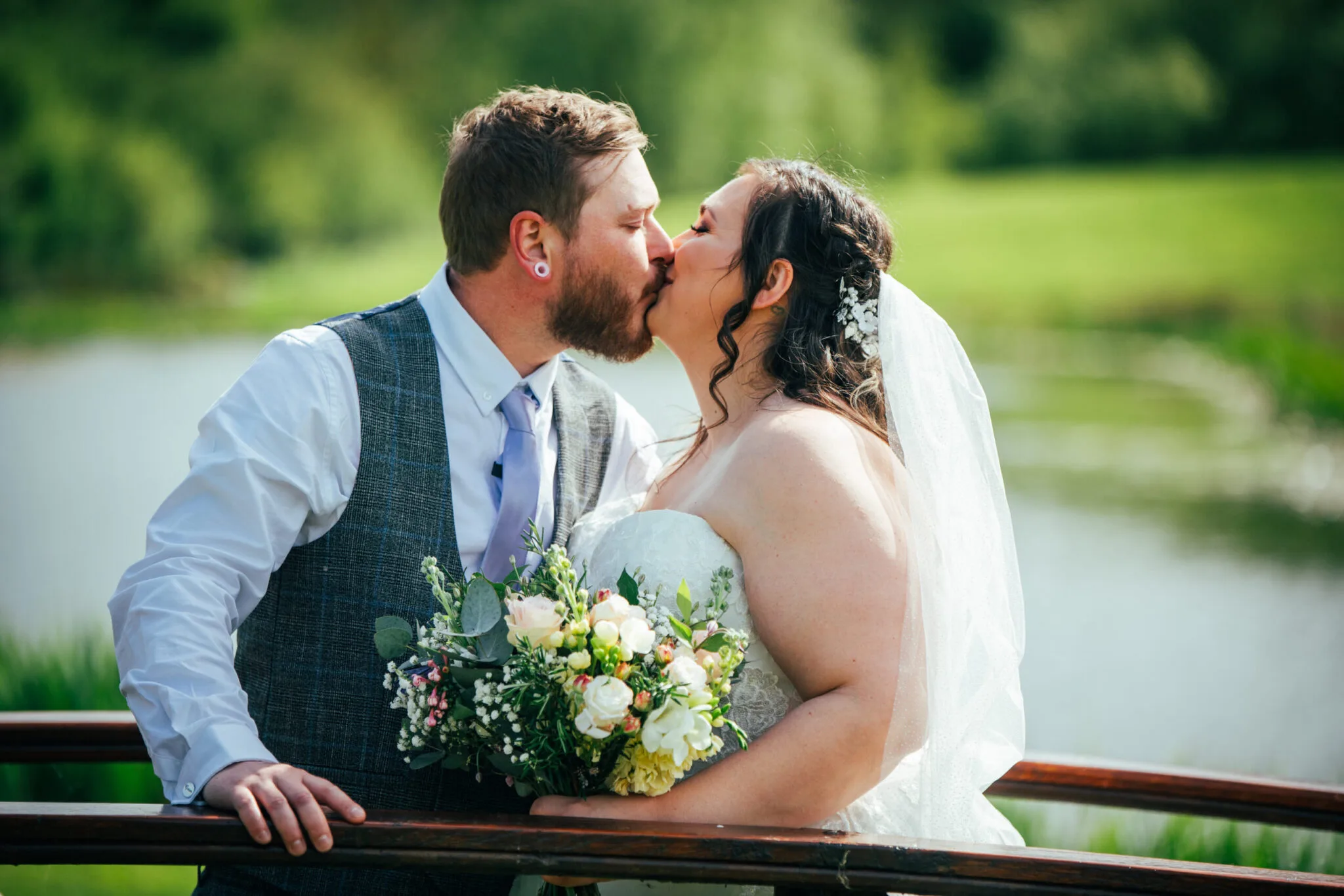 Bride and groom kissing by a lake